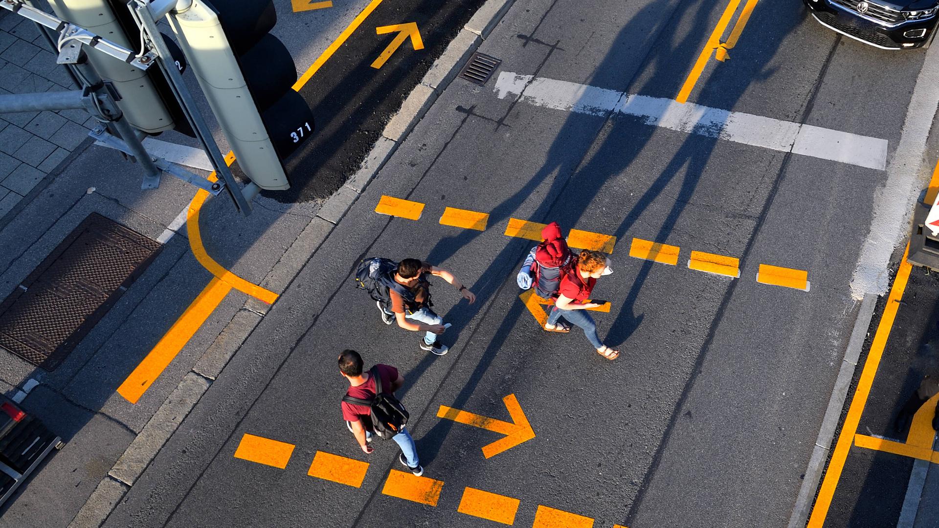 Passanten überqueren die Strasse am Fußgängerübergang.