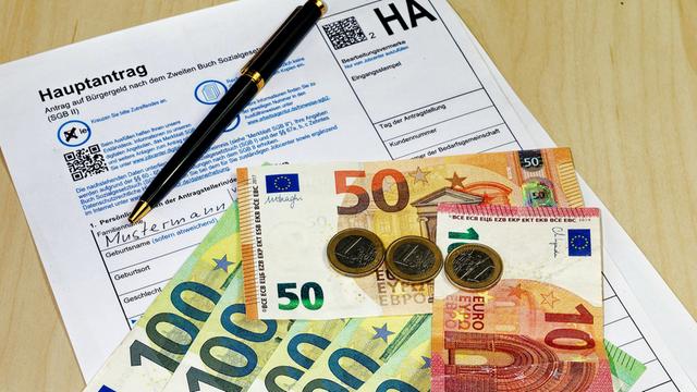 Ein Antrag für Bürgergeld und 563 Euro liegen auf dem Boden.