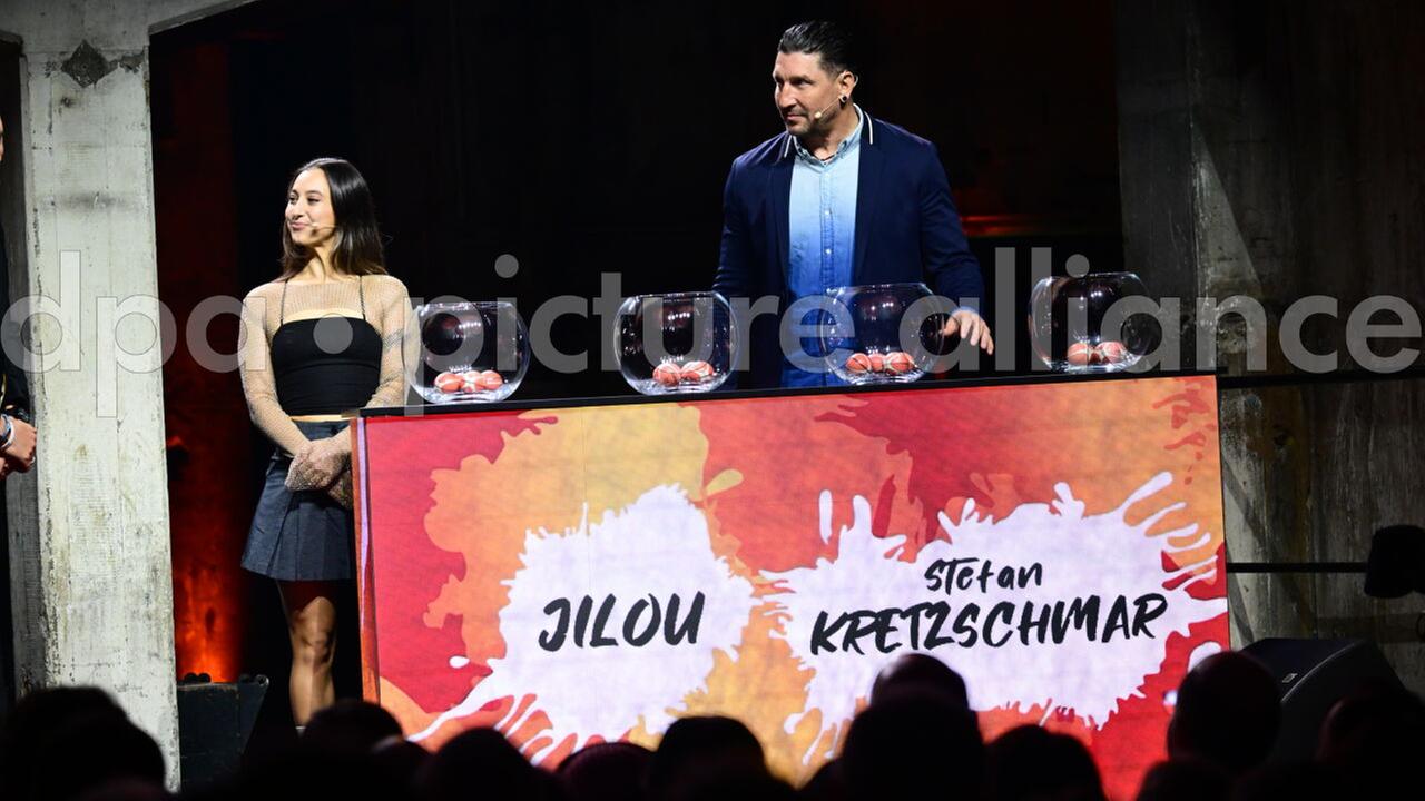 Stefan Kretzschmar (r), ehemaliger Handballspieler, und Jilou, Breakdancerin, nehmen an der Auslosung für die FIBA-Basketball-Weltmeisterschaft der Frauen 2026 teil. Sie stehen auf einer Bühne vor vier Glasbehältern mit den Losen.