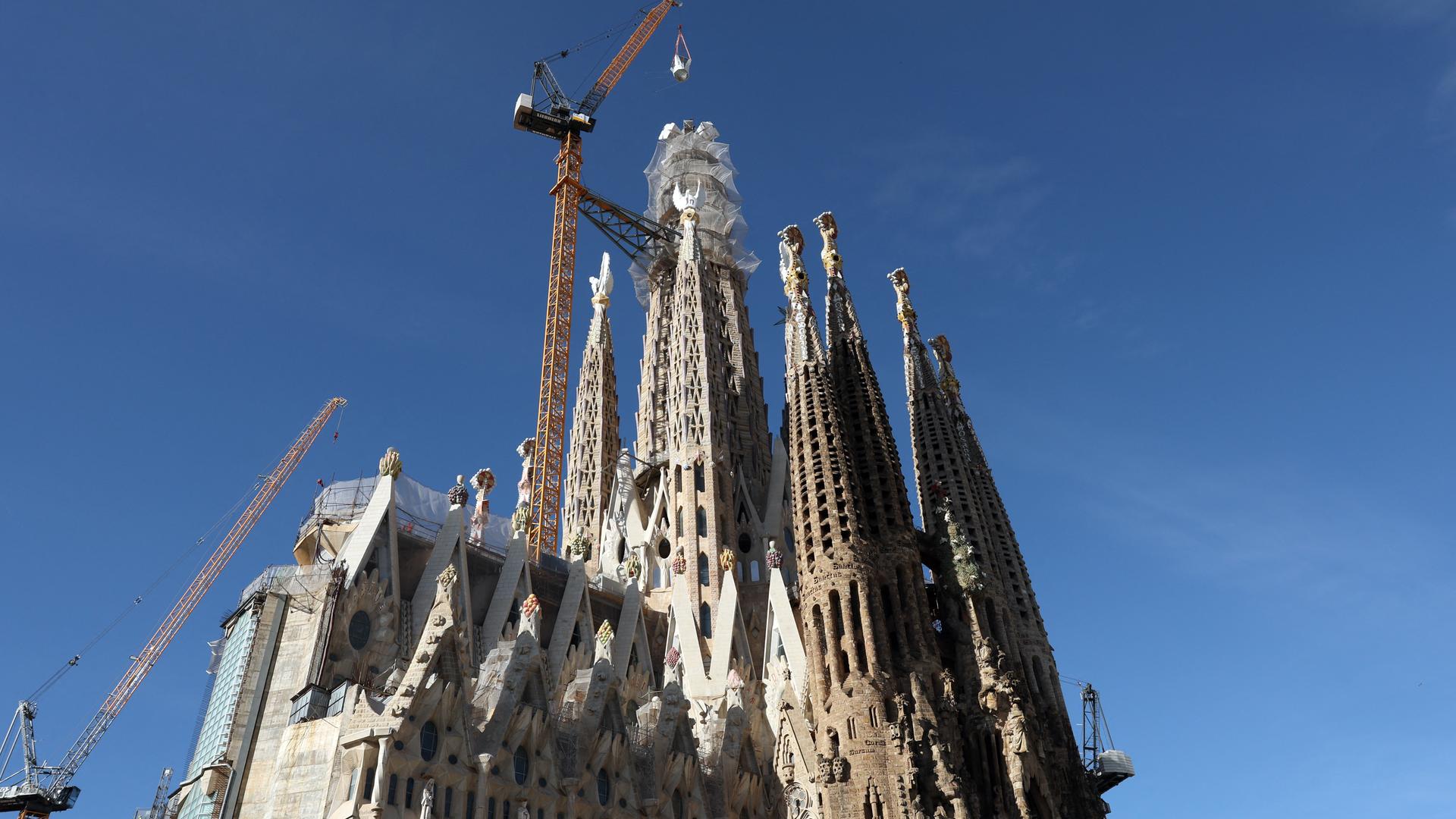 Ein Kran hebt das letzte Teilstück eines Kreuzes auf den Turm der Sagrada Familia in Barcelona. Ein Kran hebt das letzte Teilstück eines Kreuzes auf den Turm der Sagrada Familia in Barcelona.