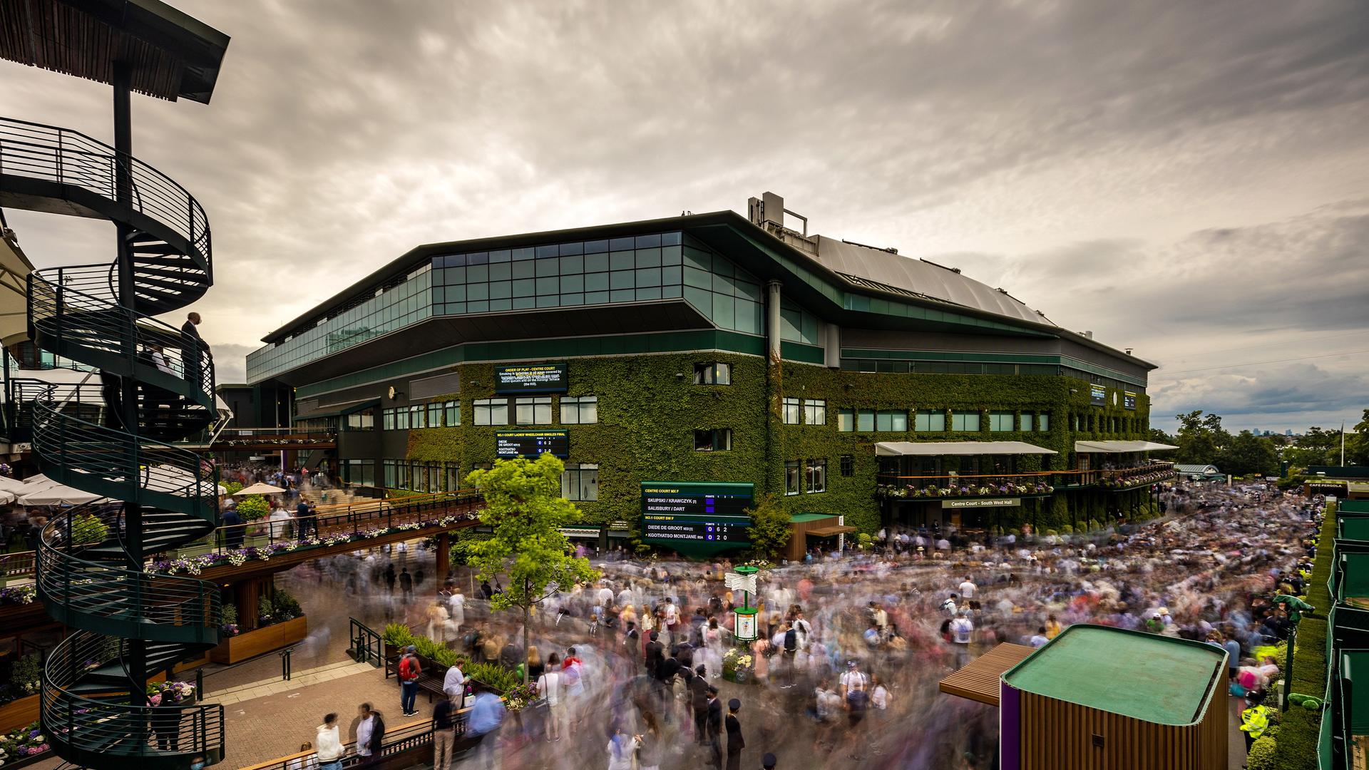 Tennisfans sind auf den Gehwegen rund um den Centre Court des Tennisturniers in Wimbledon unterwegs. Tennisfans sind auf den Gehwegen rund um den Centre Court des Tennisturniers in Wimbledon unterwegs.