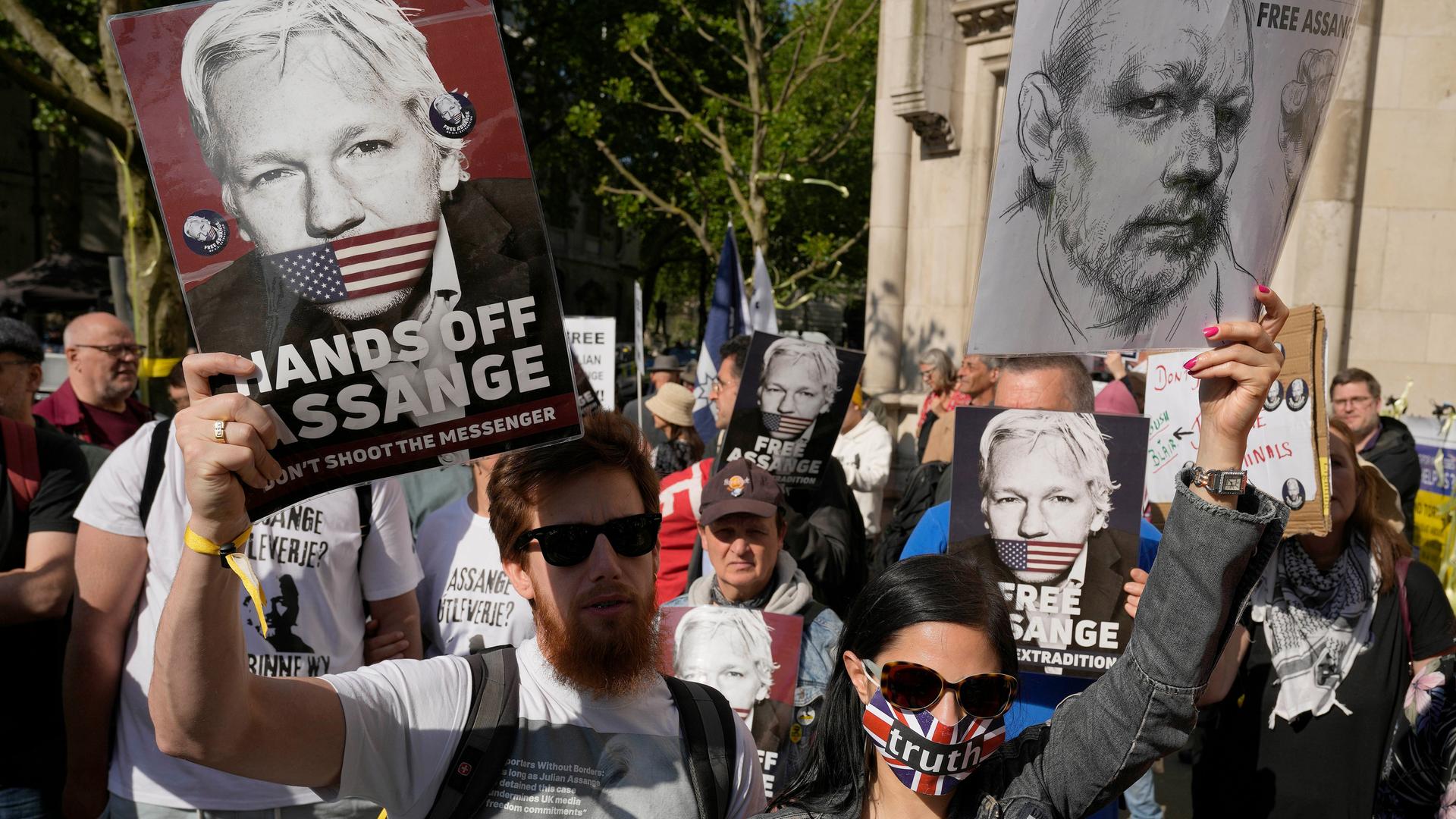 Demonstranten halten Plakate mit Bildern von Julian Assange in die Luft.