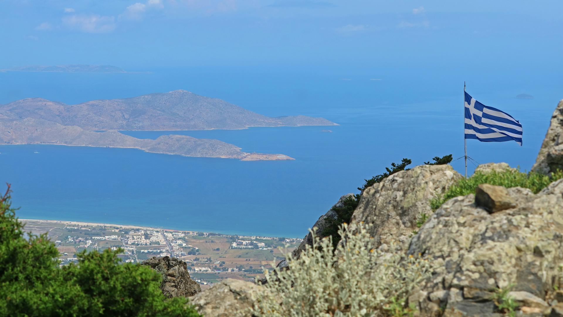 Griechische Flagge auf einem Berg mit Blick auf die Küste. Griechische Flagge auf einem Berg mit Blick auf die Küste.