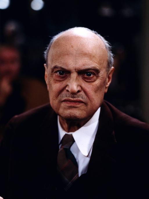 Ein Portrait von 1983 zeigt Sebastian Haffner, den bedeutenden deutsch-britischen Historiker, Publizist, Schriftsteller und Journalist. Er trägt einen Anzug und schaut mit ernster Miene in die Kamera.