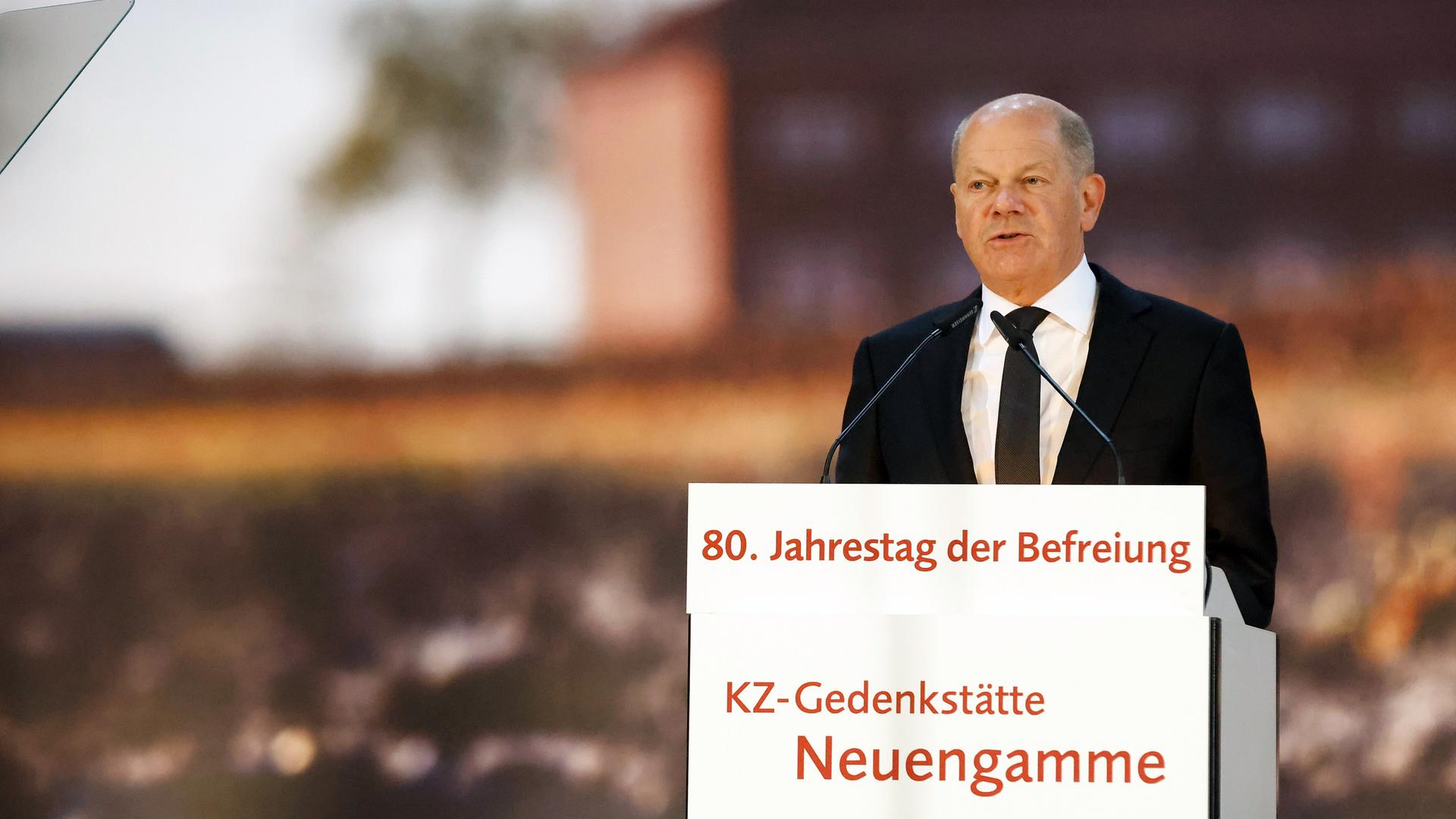 Scholz hinter einem Rednerpult im dunklen Anzug und mit dunkler Krawatte
