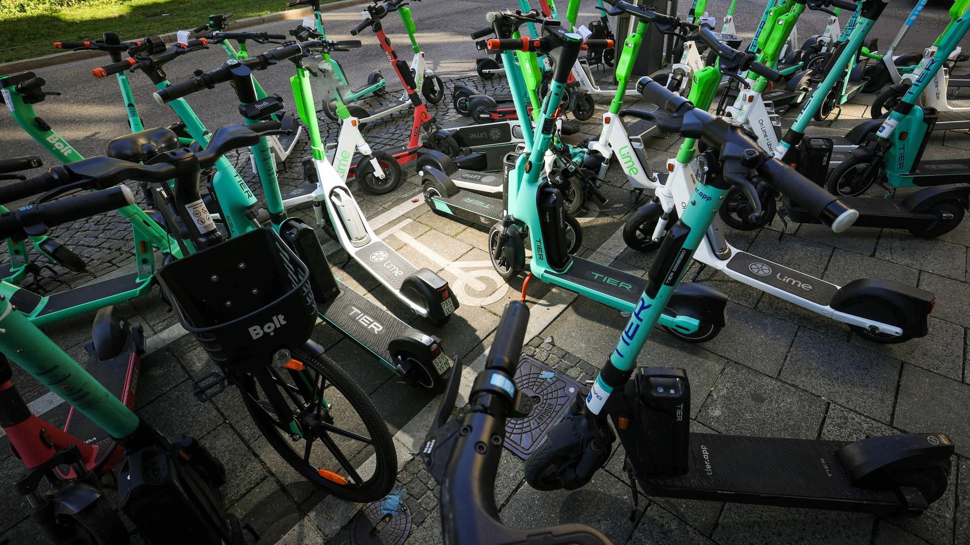 Elektroroller verschiedener Marker und Verleihfirmen stehen chaotisch auf einem überfüllten E-Scooter Parkplatz in München. Elektroroller verschiedener Marker und Verleihfirmen stehen chaotisch auf einem überfüllten E-Scooter Parkplatz in München.