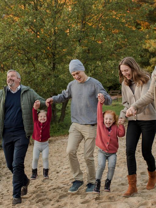 Familie verbringt ihre Freizeit miteinander beim Spazierengehen im Sand Familie verbringt ihre Freizeit miteinander beim Spazierengehen im Sand