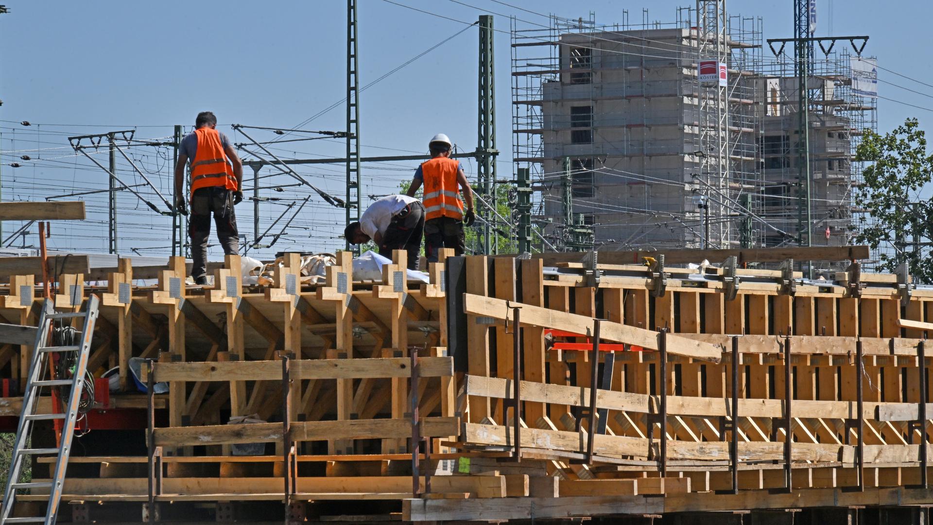 Arbeiter auf einer Baustelle mit Gerüsten vor einem eingerüsteten Gebäude in Erfurt 