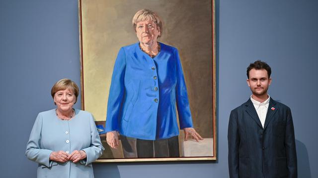 Das Foto zeigt das Bild von der früheren Bundes-Kanzlerin Angela Merkel. Vor dem Bild stehen Angela Merkel und ein junger Mann.