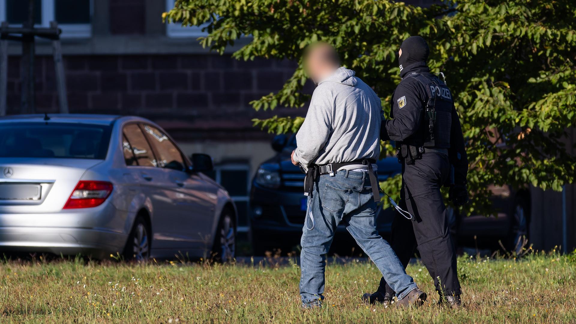 02.10.2025, Baden-Württemberg, Karlsruhe: Ein Mann wird von einem Bundespolizisten von einem Helikopter (nicht im Bild) zu einem Fahrzeug der Bundespolizei geführt.