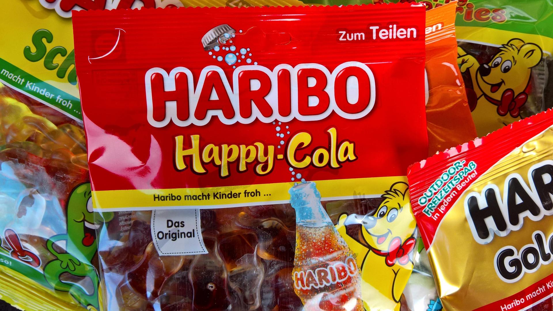 Happy-Cola und Goldbären von Haribo liegen auf einem Tisch. Happy-Cola und Goldbären von Haribo liegen auf einem Tisch.
