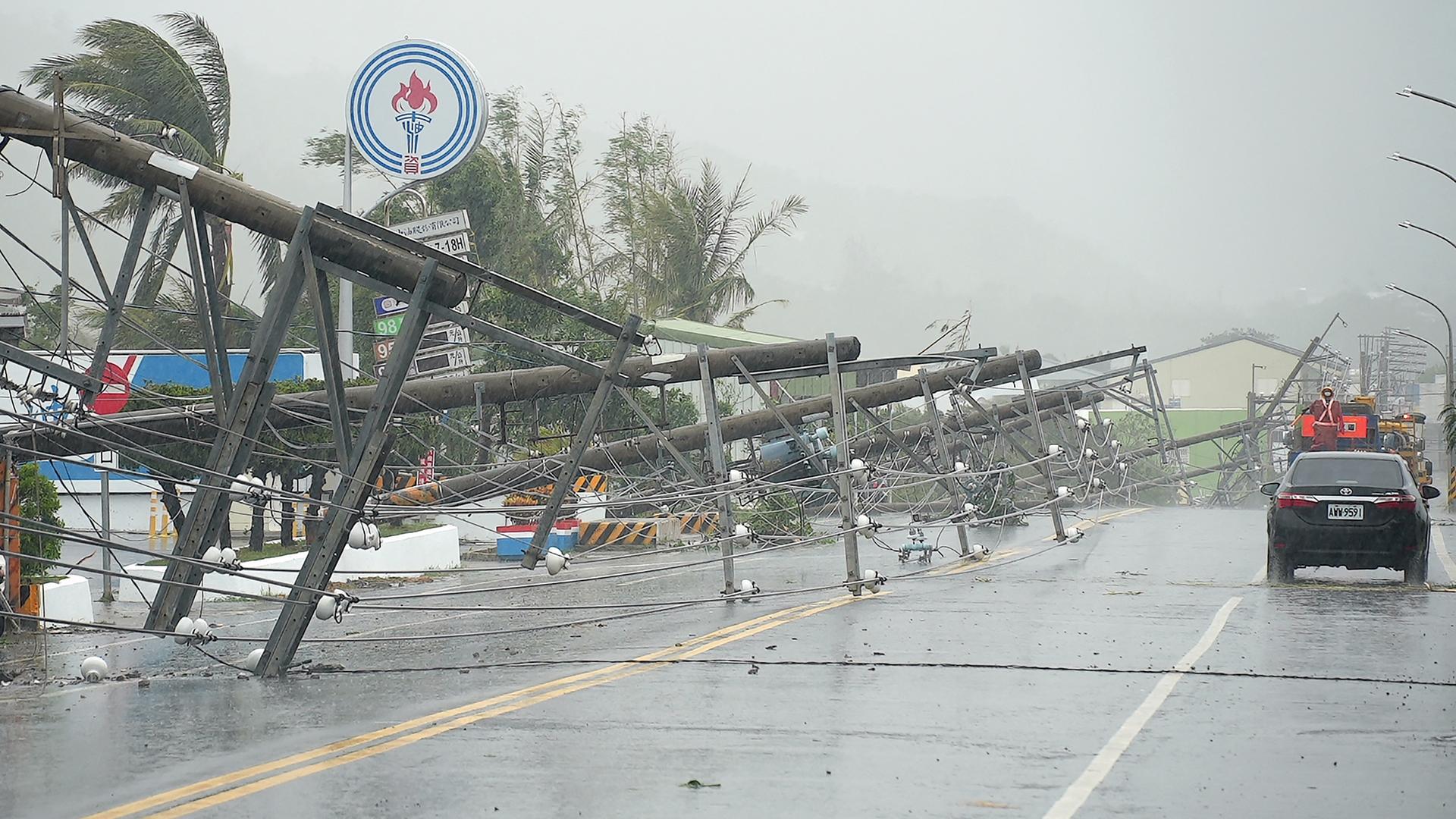 Ein Auto fährt an Stromleitungen vorbei, die durch den Taifun Koinu in Taiwan umgestürzt sind.