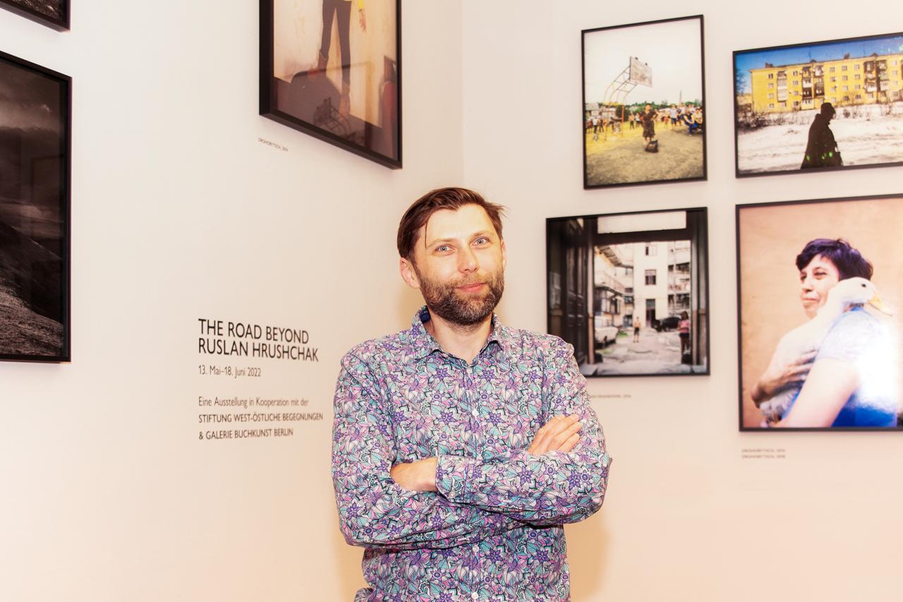 Ein junger Mann steht vor mehreren Fotos in einer Galerie.