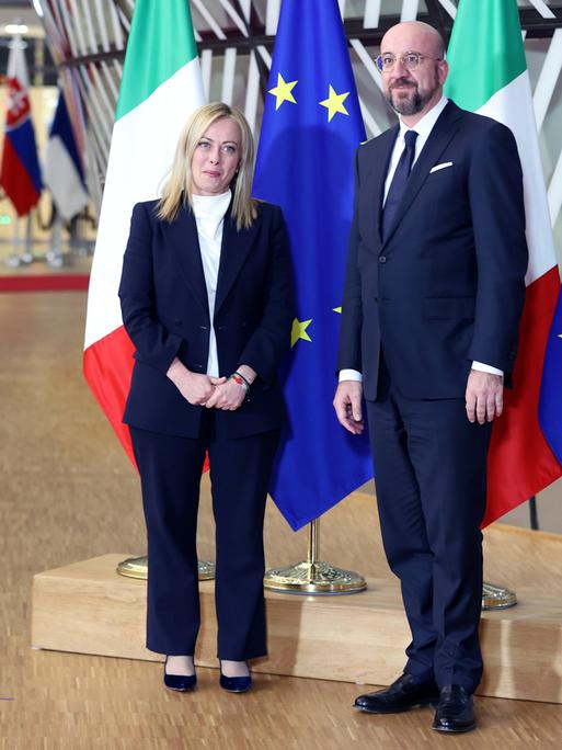 Italiens neue Regierungschefin Giorgia Meloni und der Präsident des Europäisches Rats Charles Michel stehen vor Flaggen Italiens und der EU. 