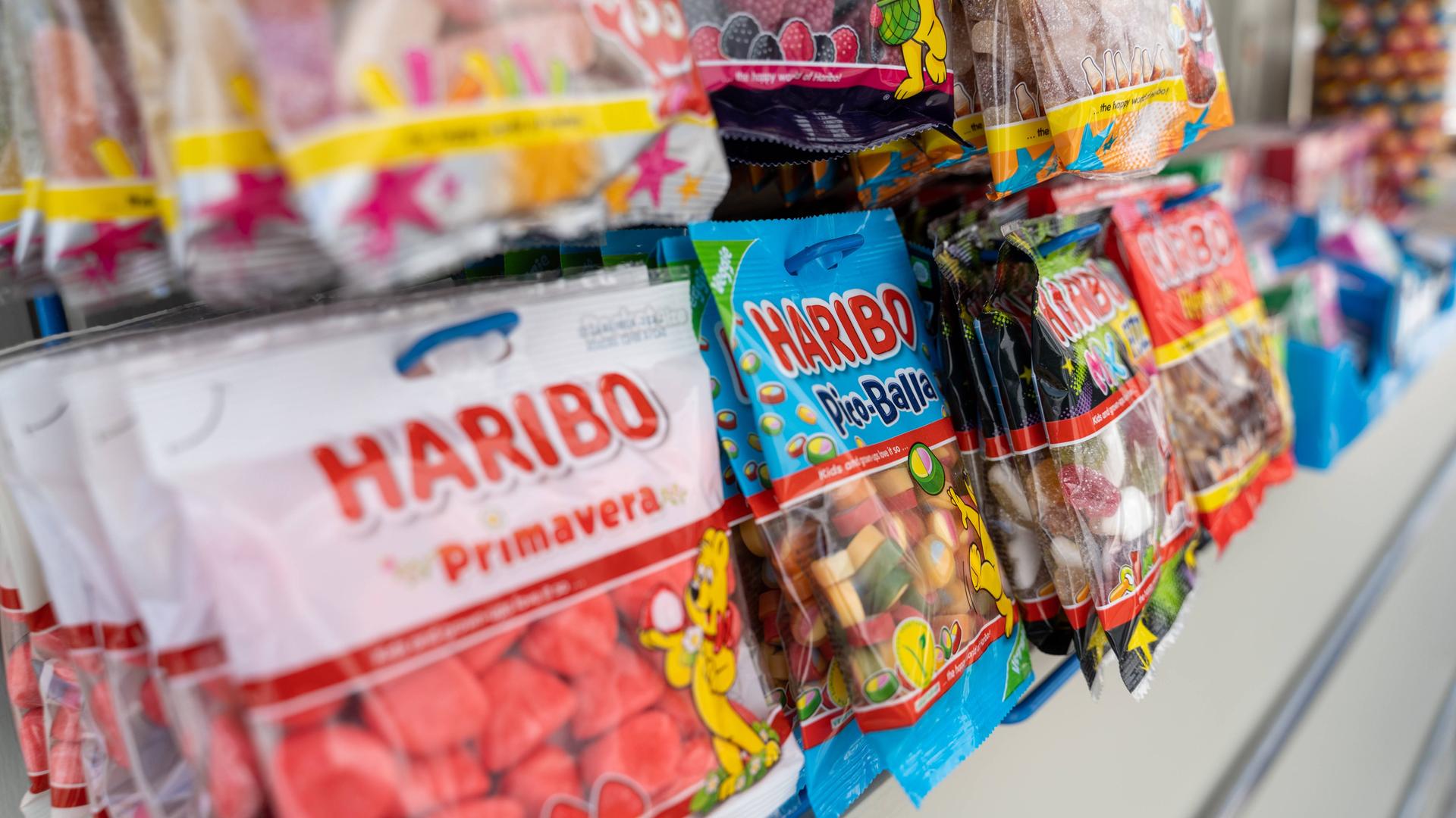 Mehrere Packungen Haribo hängen an einem Kiosk.