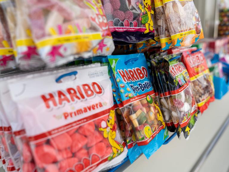 Mehrere Packungen Haribo hängen an einem Kiosk.