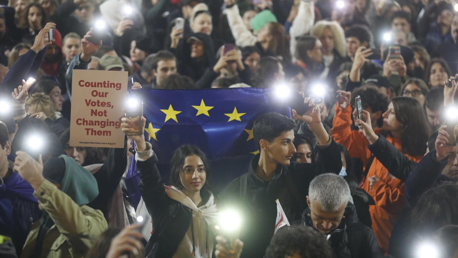 Menschen nehmen an einer Kundgebung der Opposition teil vor dem Parlamentsgebäude im Zentrum von Tbilisi.