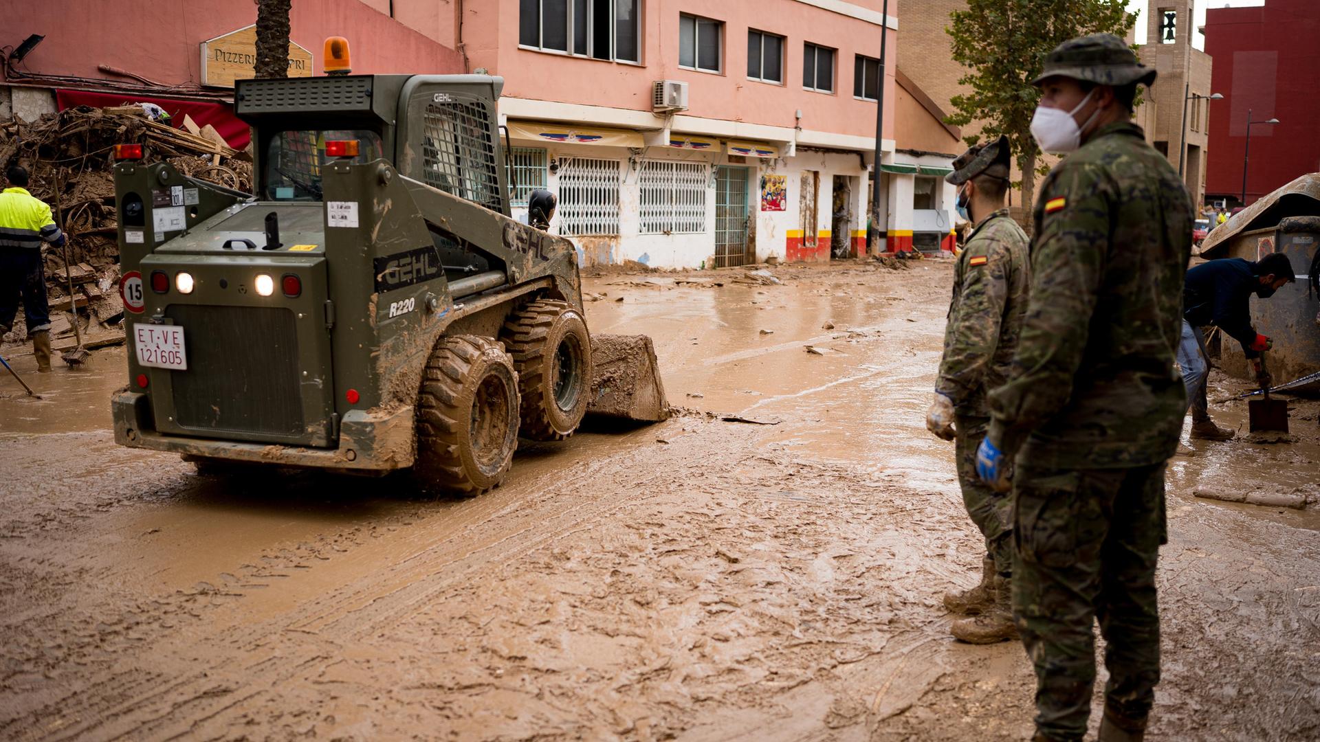 Ein militärisches Räumfahrzeug und zwei Soldaten helfen bei den Aufräumarbeiten der Flutkatastrophe in Spanien im Herbst 2024.