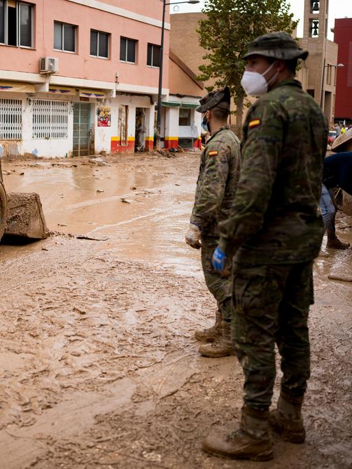 Ein militärisches Räumfahrzeug und zwei Soldaten helfen bei den Aufräumarbeiten der Flutkatastrophe in Spanien im Herbst 2024.