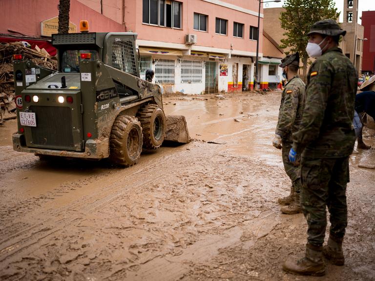 Ein militärisches Räumfahrzeug und zwei Soldaten helfen bei den Aufräumarbeiten der Flutkatastrophe in Spanien im Herbst 2024.