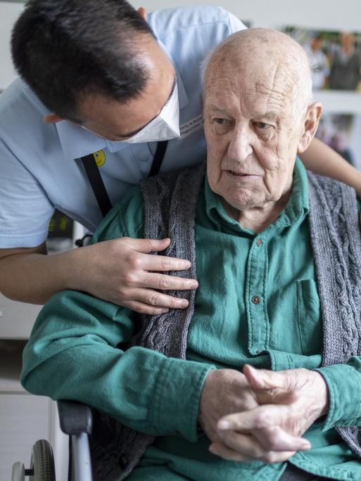 Altenpfleger redet mit einem Bewohner im Pflegeheim