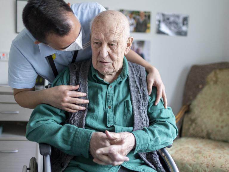 Altenpfleger redet mit einem Bewohner im Pflegeheim