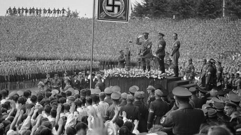 Historische Aufnahme vom Aufmarsch beim 10. Reichsparteitag der NSDAP im Stadion von Nürnberg am 10. September 1938: Hitler mit dem Reichsjugendführer Baldur von Schirach und Rudolf Heß auf der Tribüne. 