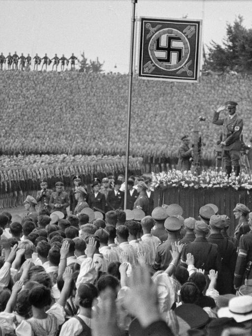 Historische Aufnahme vom Aufmarsch beim 10. Reichsparteitag der NSDAP im Stadion von Nürnberg am 10. September 1938: Hitler mit dem Reichsjugendführer Baldur von Schirach und Rudolf Heß auf der Tribüne. 