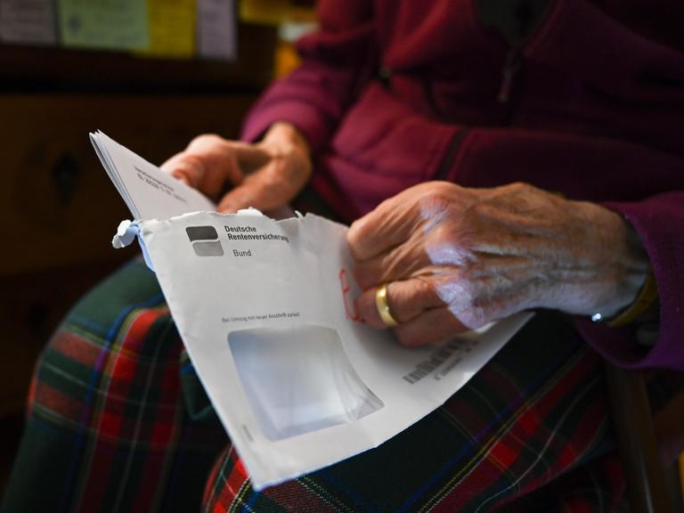 Eine Seniorin hält ihren Rentenbescheid in der Hand