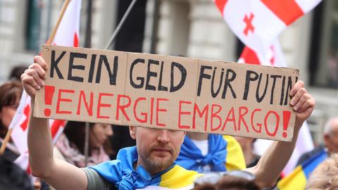 Ein Teilnehmer einer Kundgebung gegen den Krieg in der Ukraine hält bei einem Demonstrationszug durch die Innenstadt ein Schild mit der Aufschrift "Kein Geld für Putin! Energie Embargo!".