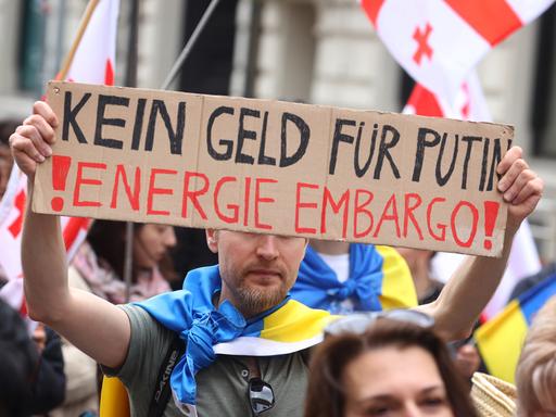 Ein Teilnehmer einer Kundgebung gegen den Krieg in der Ukraine hält bei einem Demonstrationszug durch die Innenstadt ein Schild mit der Aufschrift "Kein Geld für Putin! Energie Embargo!".
