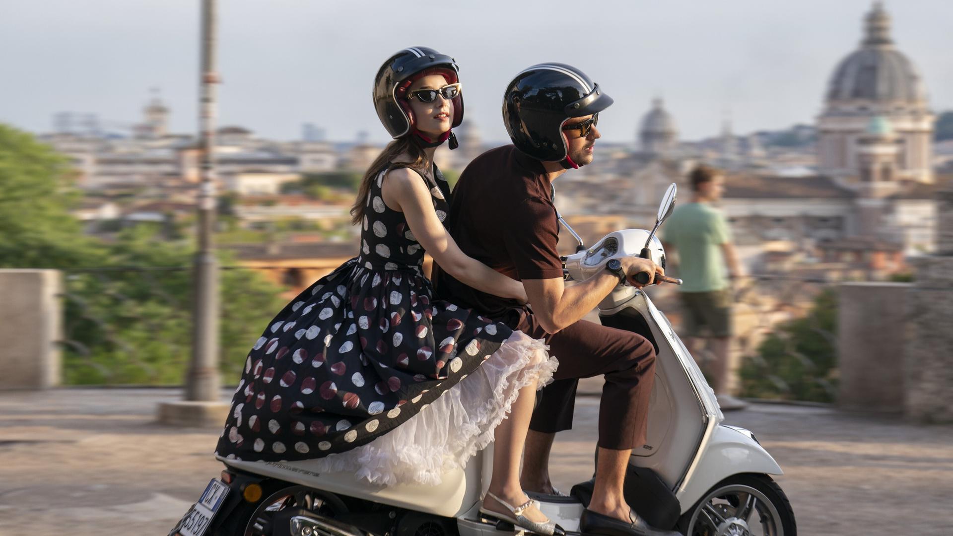 Die Schauspieler Lily Collins und Eugenio Franceschini sitzen auf einem Motorroller und fahren durch Rom. 