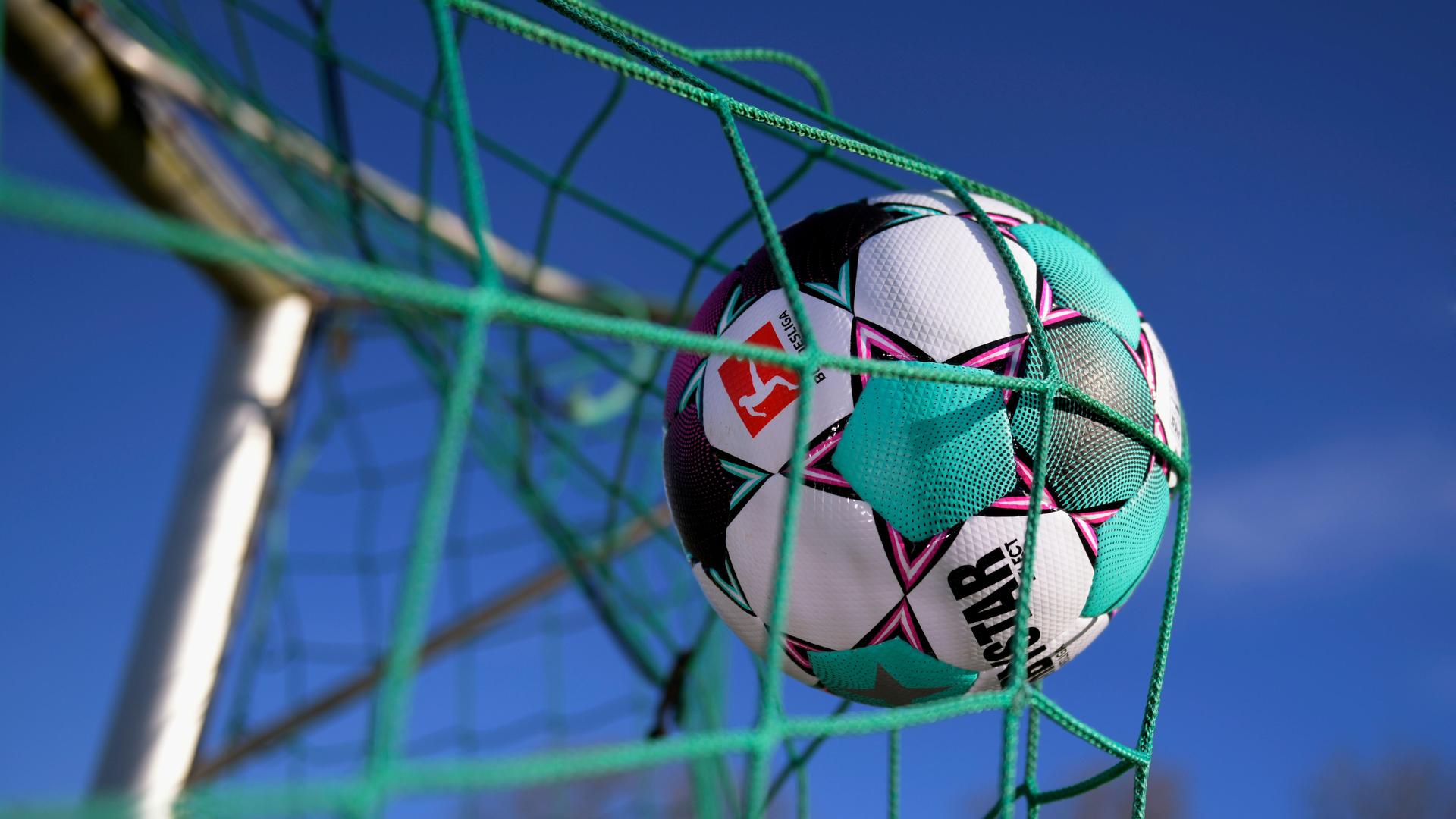 Ein Fußball mit dem Logo der Bundesliga fliegt ins Tornetz. Ein Fußball mit dem Logo der Bundesliga fliegt ins Tornetz.