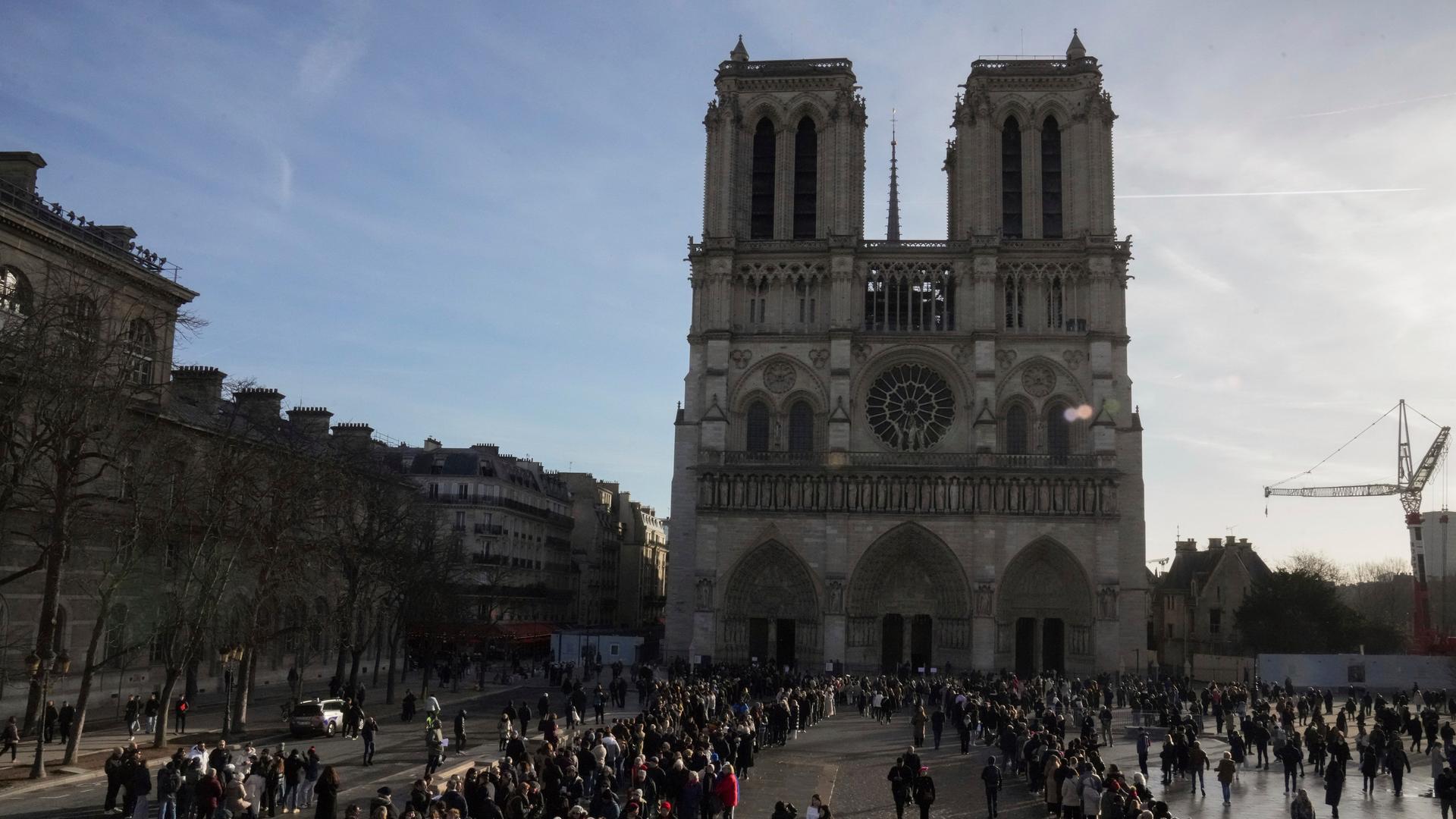 Menschen warten vor der Kathedrale Notre Dame in Paris, um den Kirchenraum zu besuchen.