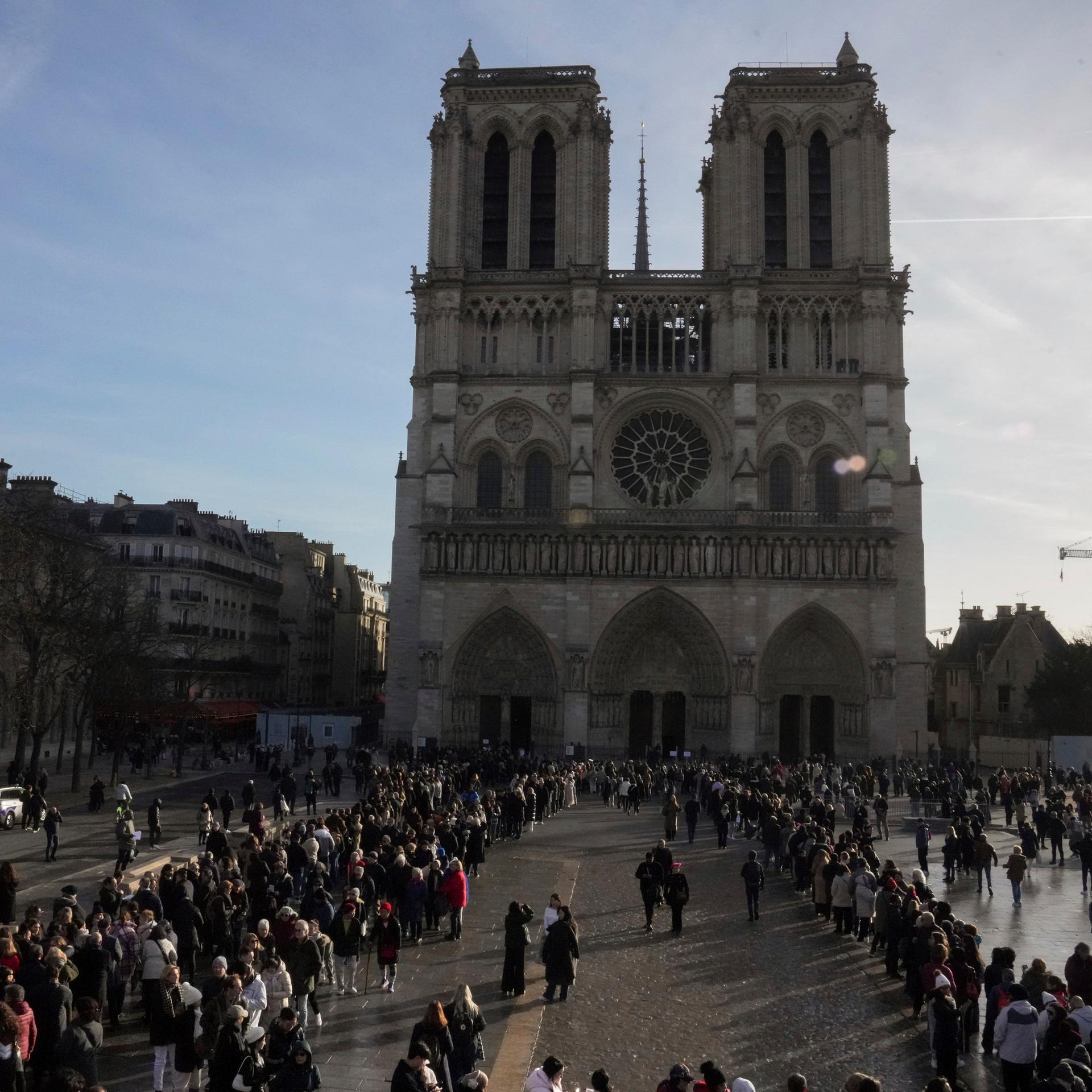 Menschen warten vor der Kathedrale Notre Dame in Paris, um den Kirchenraum zu besuchen.