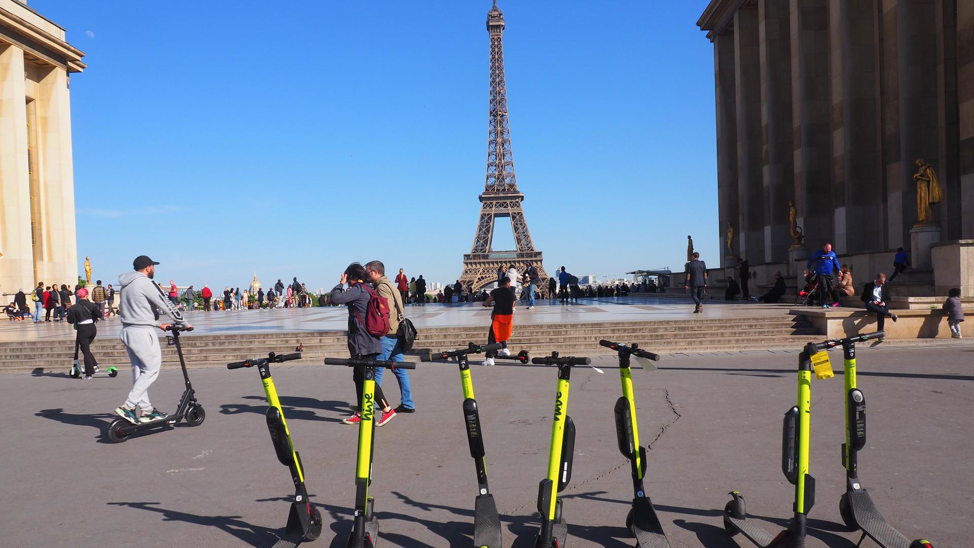 Mehrere E-Scooter stehen unweit des Pariser Eifelturms auf einem Platz.