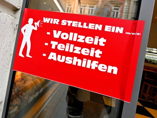 Auf einem roten Schild an der Glastür einer Bäckerei steht: "Wir stellen ein (m/w/d): Vollzeit, Teilzeit, Aushilfe" Auf einem roten Schild an der Glastür einer Bäckerei steht: "Wir stellen ein (m/w/d): Vollzeit, Teilzeit, Aushilfe"