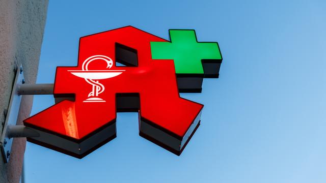 Das Logo einer Apotheke ist an der Fassade von einem Gebäude zu sehen.