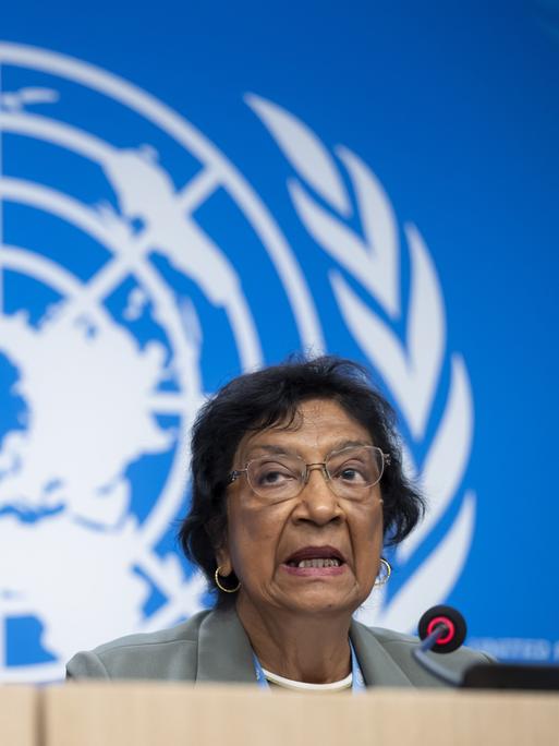 Navi Pillay spricht während einer Pressekonferenz in ein Mikro, im Hintergrund sieht man das Logo der United Nations