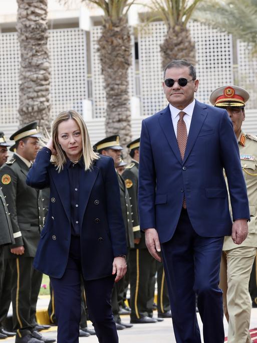 Die italienische Premierministerin Giorgia Meloni geht mit ihrem libyschen Kollegen Abdul Hamid Dbeibeh bei eine mStaatsempfang an Soldaten vorbei Richtung der Kamera.