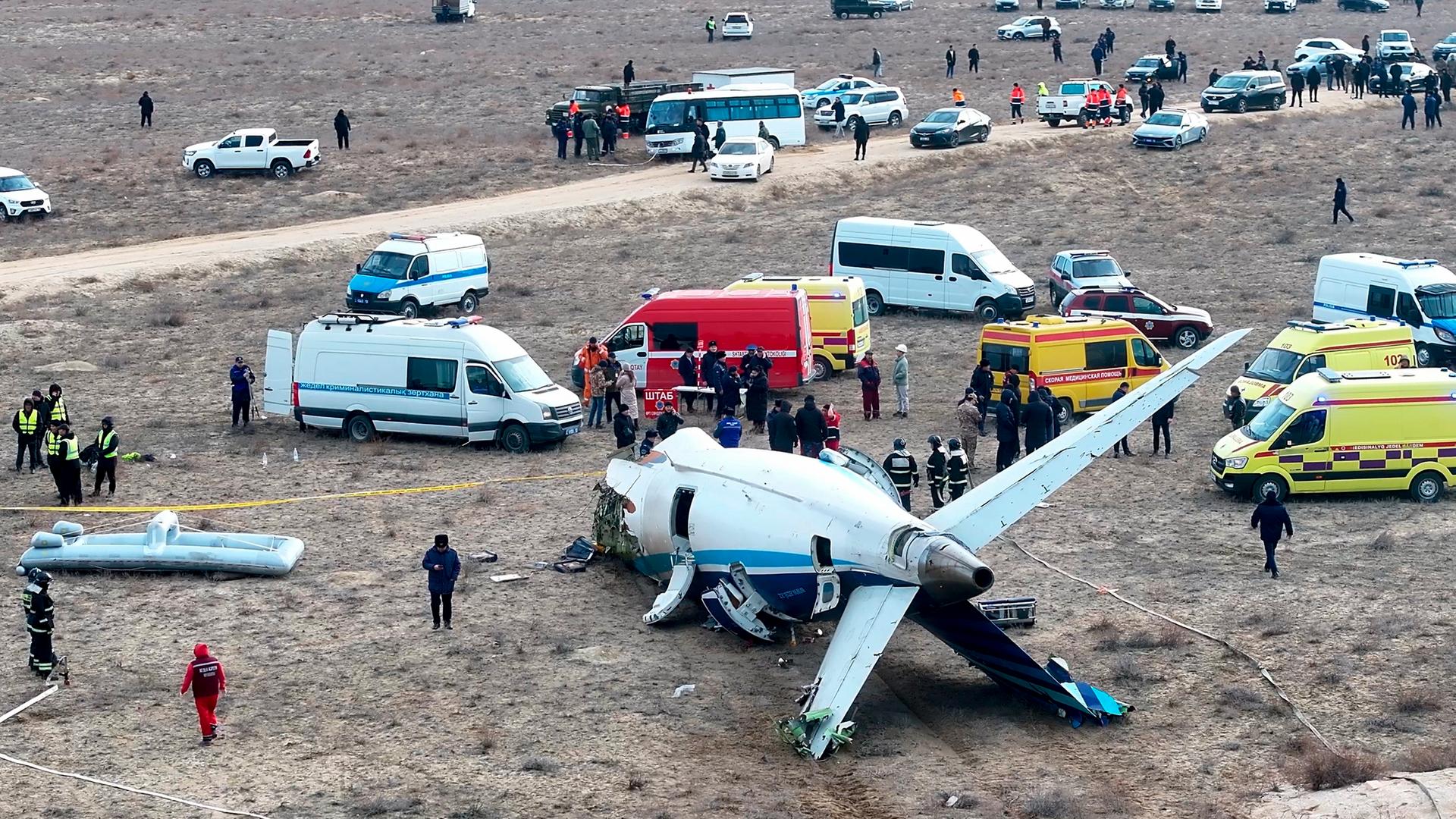 Das Wrack einer "Embraer 190" der Azerbaijan Airlines in Nähe des Flughafens von Aktau. Daneben Rettungswagen und Einsatzkräfte.