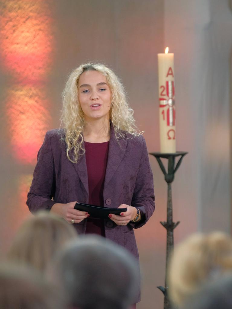 Jana Highholder steht in einer Kirche neben einer Kerze