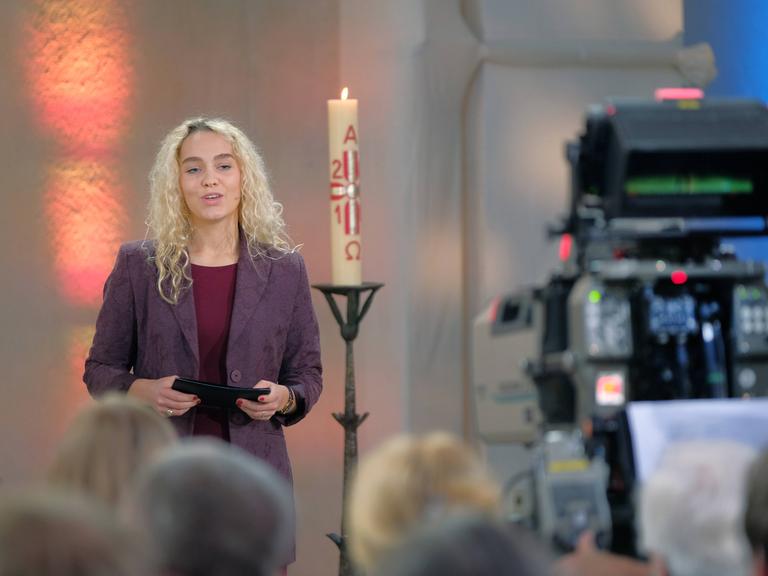 Jana Highholder steht in einer Kirche neben einer Kerze
