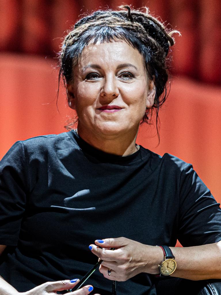 Olga Tokarczuk sitzt auf einem Stuhl auf einer Bühne und blickt lächelnd in die Kamera.