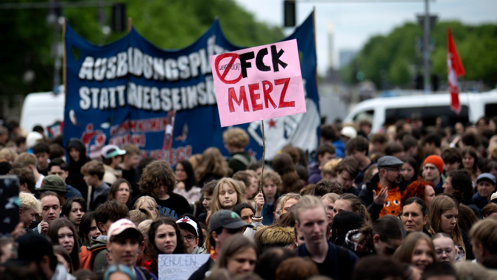 Bei einem Schulstreik gegen die Wehrpflicht im Mai 2026 hält ein Jugendlicher ein Schild "FCK MERZ" gegen Bundeskanzler Friedrich Merz in die Höhe, mitten in einer protestierenden Menschenmenge.