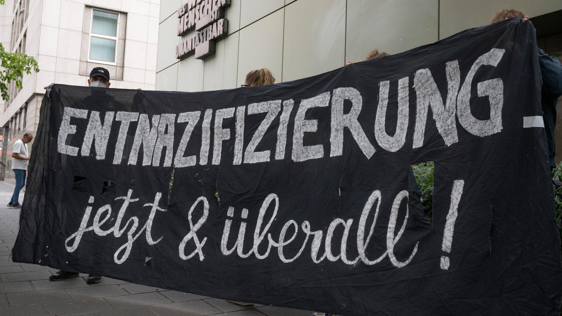„Entnazifizierung - jetzt und überall“ steht auf einem Plakat von Demonstranten.