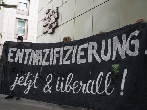 „Entnazifizierung - jetzt und überall“ steht auf einem Plakat von Demonstranten.
