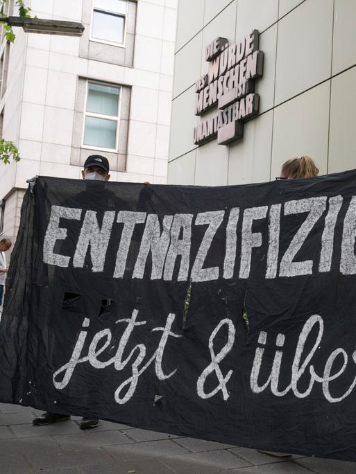 „Entnazifizierung - jetzt und überall“ steht auf einem Plakat von Demonstranten.