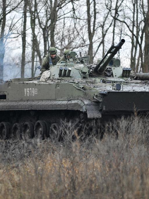 Ein Panzer und drei Soldaten bei einer Militärübung.
