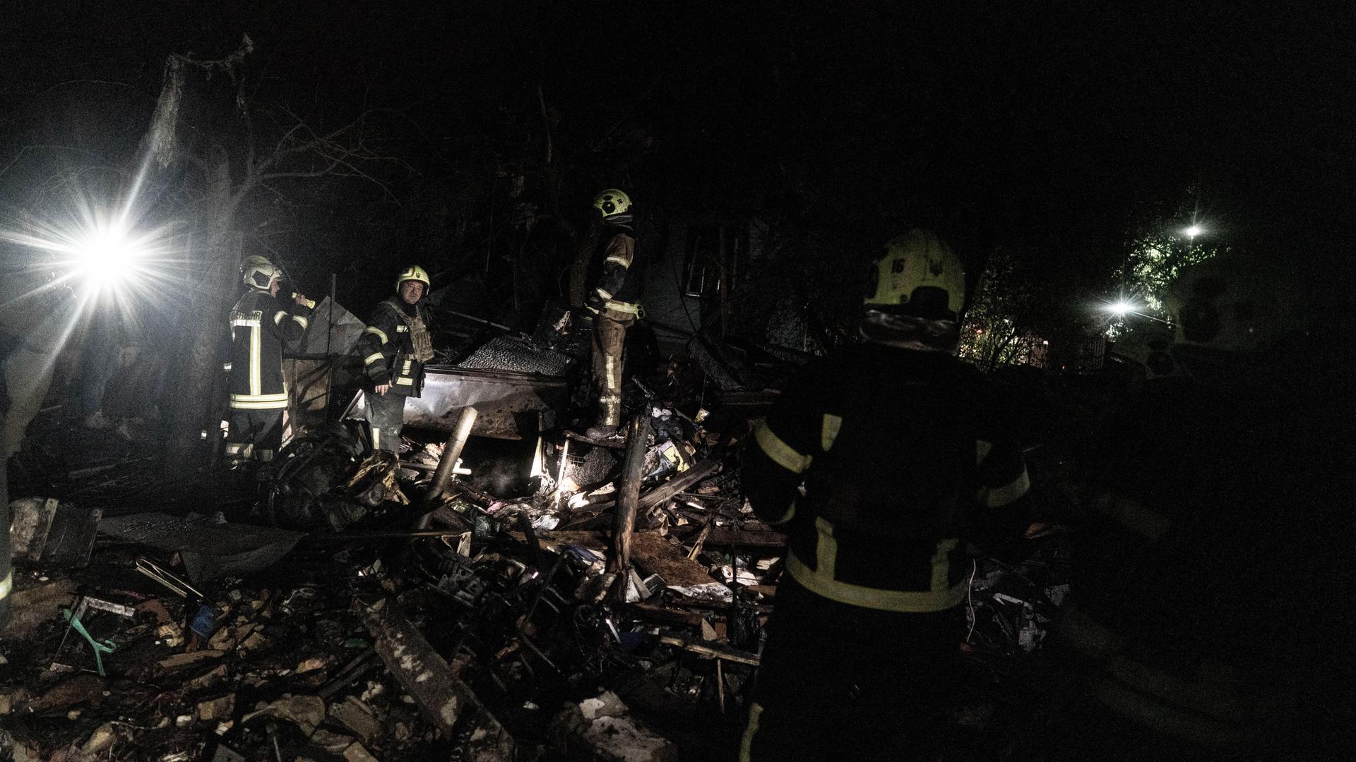Polizisten und Feuerwehrleute durchsuchen ein zerstörtes Haus in Kiew.